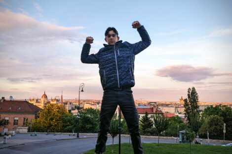 A man jumping in the air with his arms raised and bent at 90 degree angles.